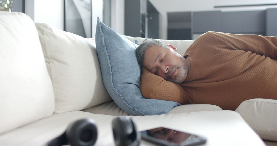 Napping Man Relaxing on Modern Couch with Headphones and Tablet Nearby - Free Images, Stock Photos and Pictures on Pikwizard.com