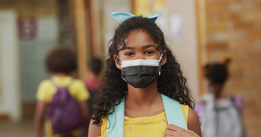 Portrait of biracial schoolgirl wearing face mask, standing in corridor looking at camera - Free Images, Stock Photos and Pictures on Pikwizard.com