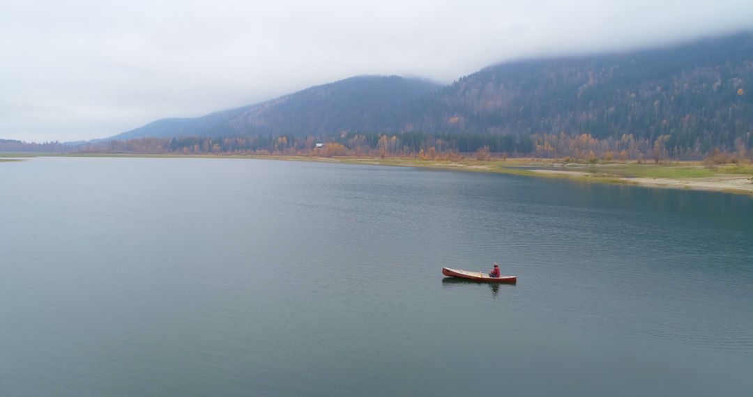 Solitary Canoe on Peaceful Lake with Foggy Mountains - Free Images, Stock Photos and Pictures on Pikwizard.com