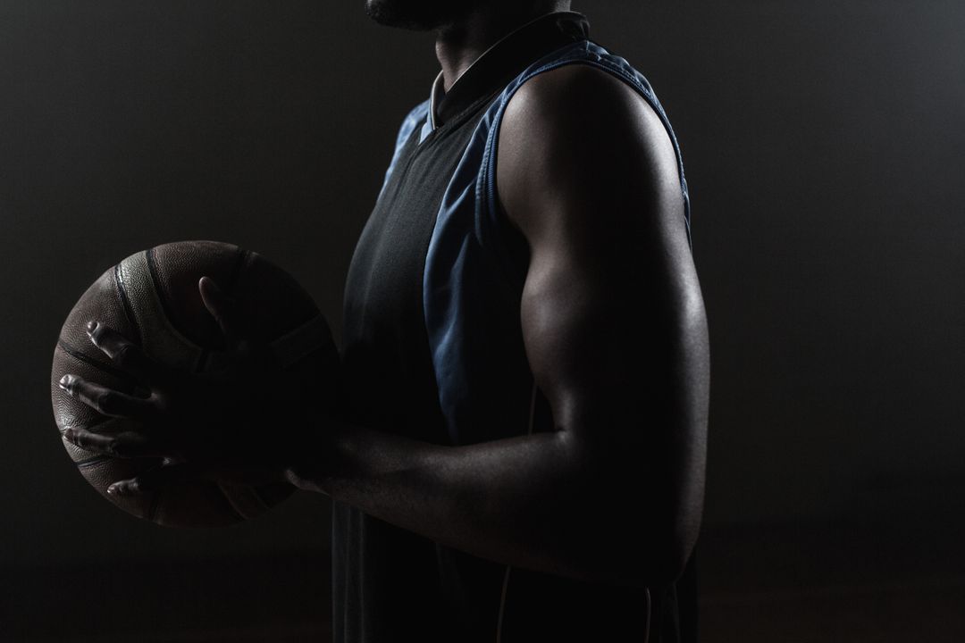 Basketball Player Holding Ball in Dark Background - Free Images, Stock Photos and Pictures on Pikwizard.com