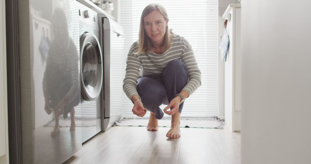 Woman checking under washing machine in laundry room - Free Images, Stock Photos and Pictures on Pikwizard.com