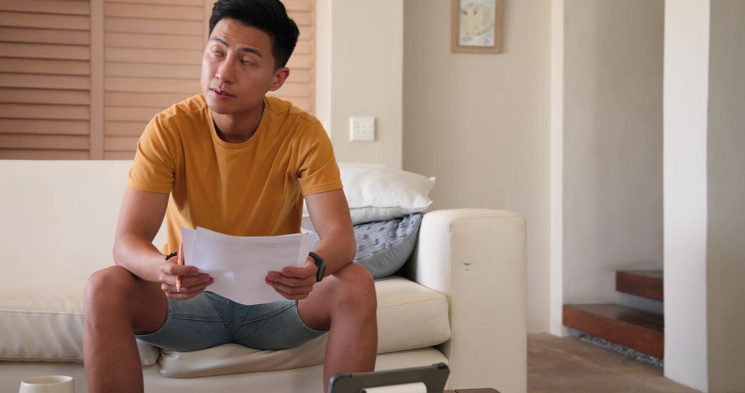 Man Relaxing on Sofa with Documents Planning at Home