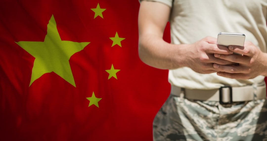 Soldier in Camouflage Using Smartphone with Chinese Flag Backdrop