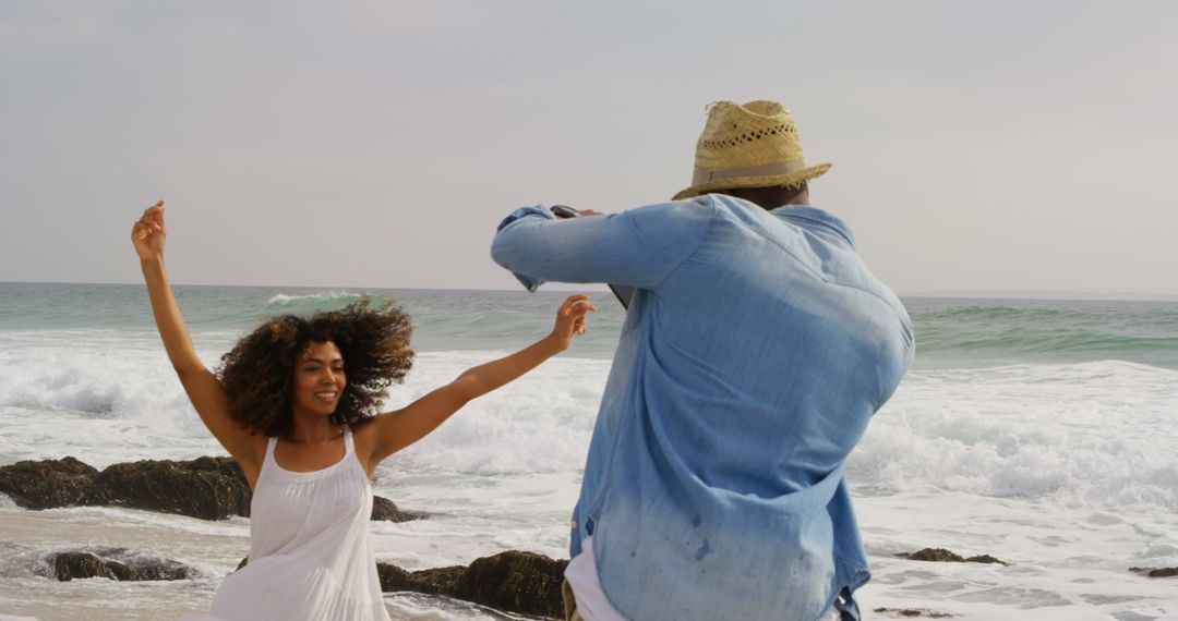 Man Photographing Woman Dancing on Scenic Beach