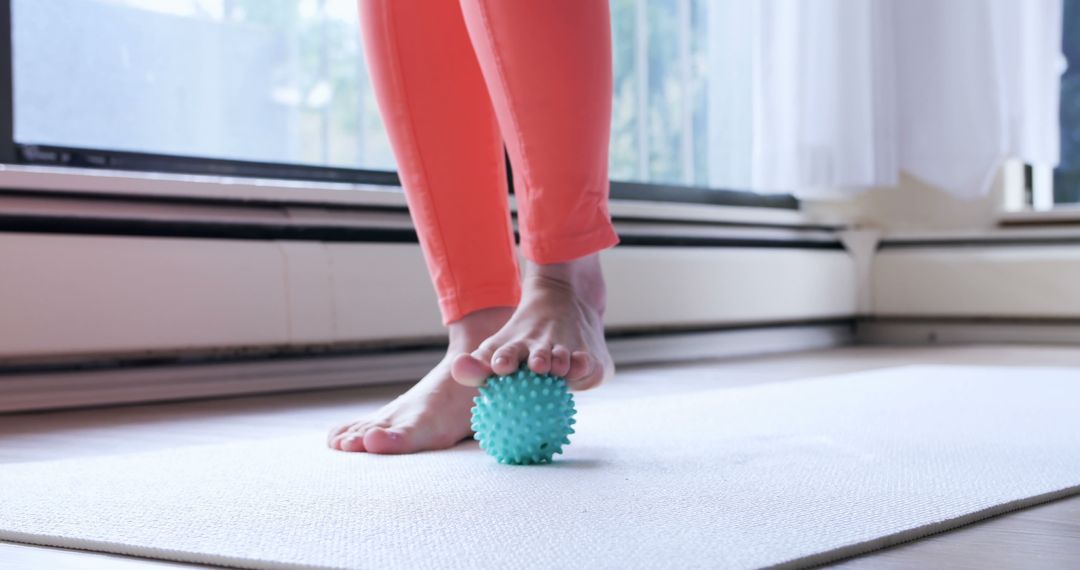 A person performs myofascial release on their foot with a massage ball to ease muscle tightness. - Free Images, Stock Photos and Pictures on Pikwizard.com