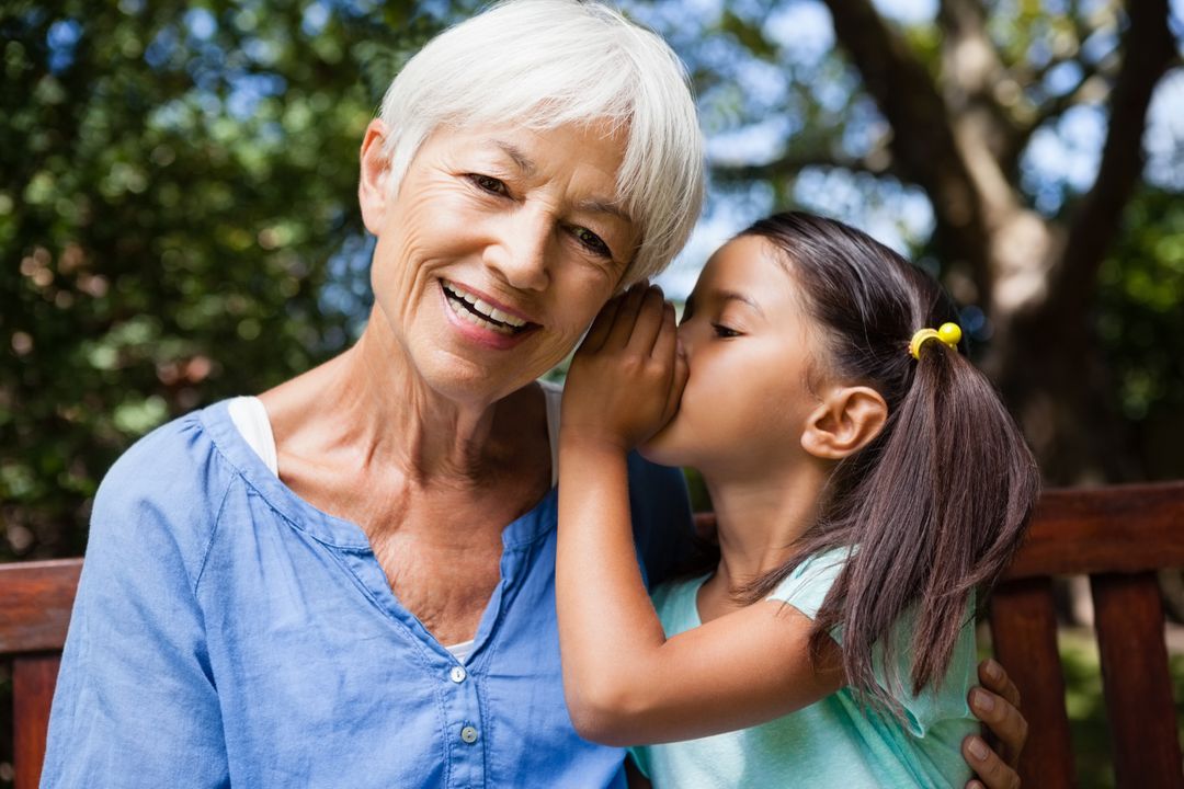 Girl whispering in ears of smiling grandmother - Free Images, Stock Photos and Pictures on Pikwizard.com