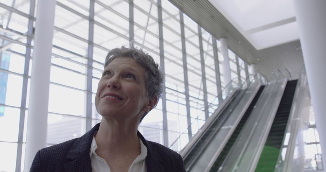 Confident Senior Businesswoman in Modern Office Building with Escalators - Free Images, Stock Photos and Pictures on Pikwizard.com