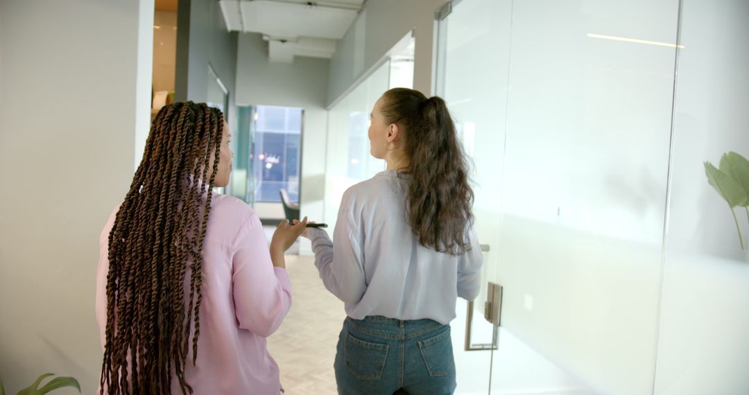 Colleagues Discussing Work Walking Through Office Hallway