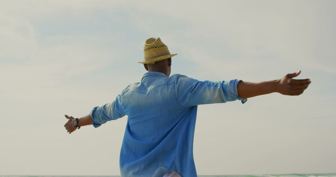 Joyful Man Enjoying Freedom with Open Arms on Beach Day