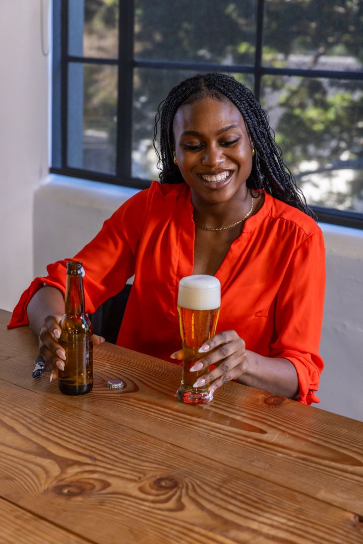 Smiling Woman Enjoying Beer at Rustic Tavern Table