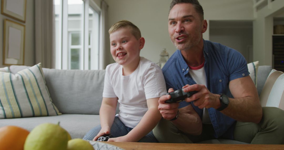 Father and Son Enjoying Video Games on Couch in Living Room - Free Images, Stock Photos and Pictures on Pikwizard.com