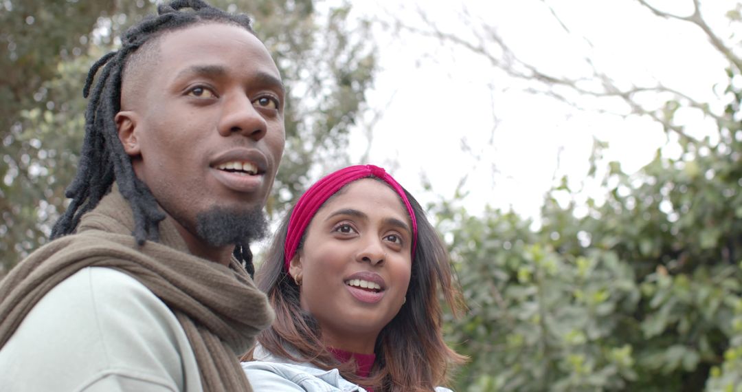 Multicultural Couple Looking Up in Park Smiling and Observing Nature on Overcast Day