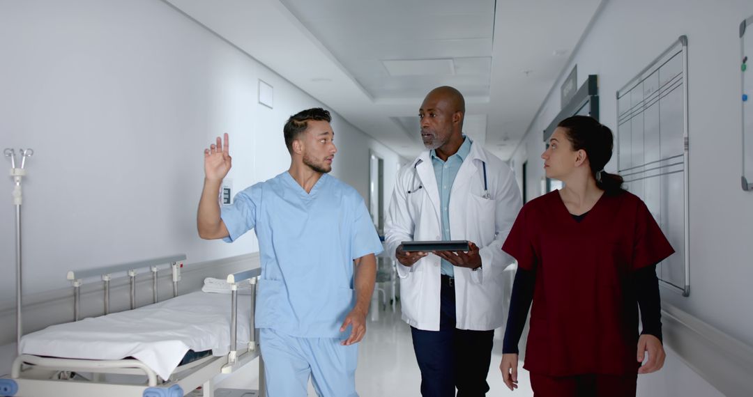 Medical Team Walking Down Hospital Corridor Discussing Patient Care - Free Images, Stock Photos and Pictures on Pikwizard.com