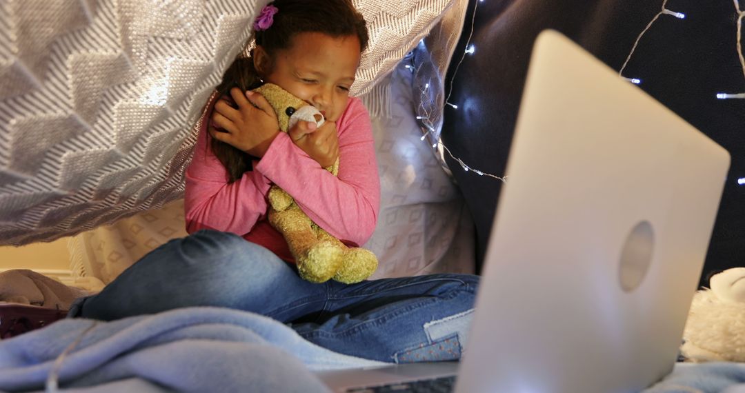 Young Girl Watching Laptop in Indoor Fort with String Lights - Free Images, Stock Photos and Pictures on Pikwizard.com