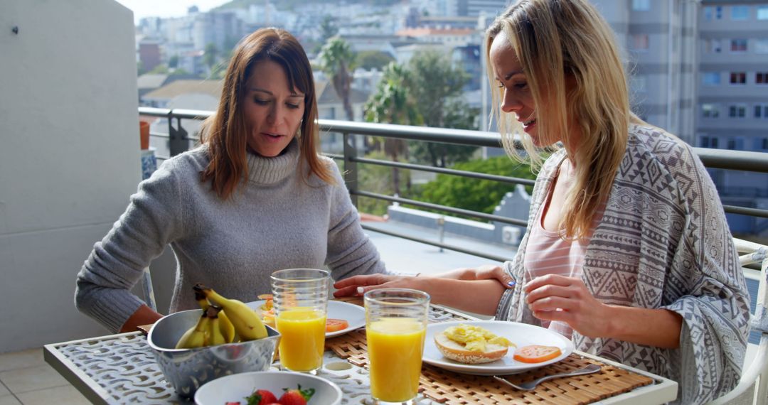 Two women enjoying breakfast together on a balcony - Free Images, Stock Photos and Pictures on Pikwizard.com