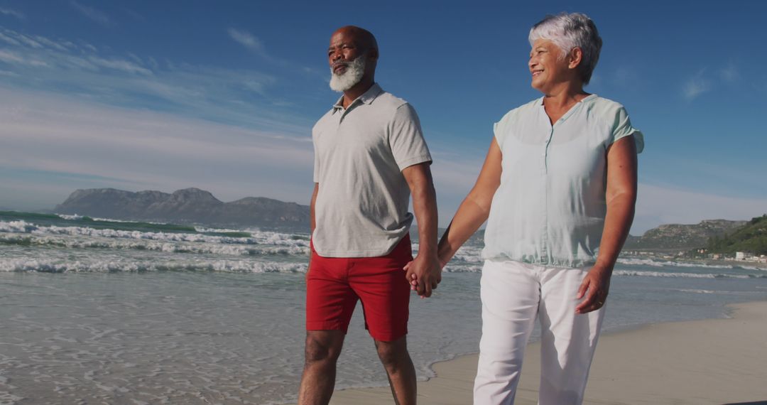 Senior Couple Walking Hand in Hand on Tranquil Beach