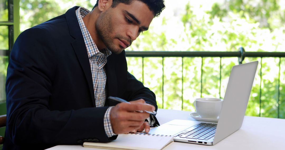 Focused Businessman Writing Notes in Notebook at Desk - Free Images, Stock Photos and Pictures on Pikwizard.com