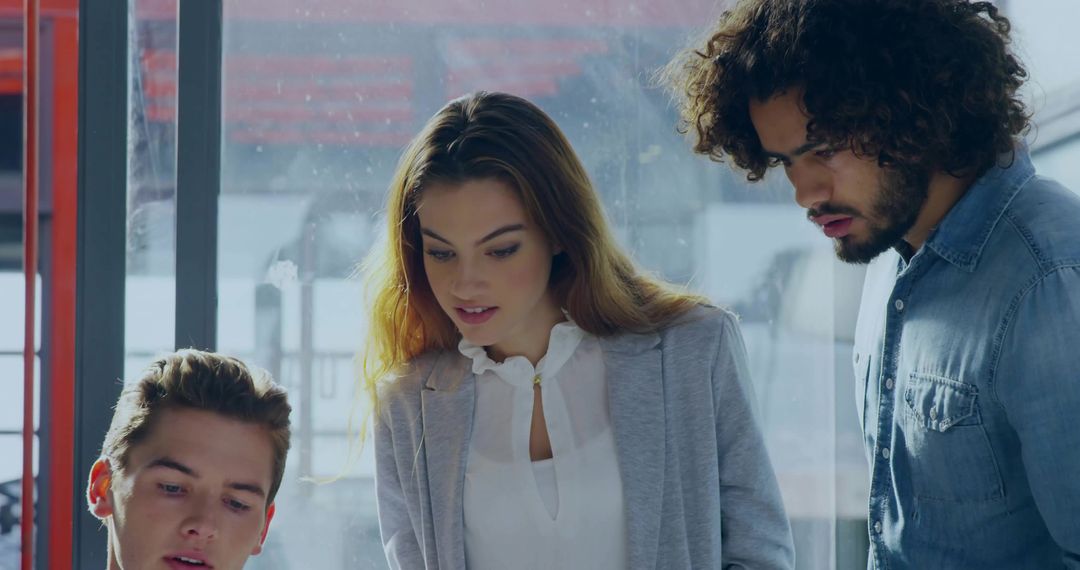 Focused Team Collaborating on Laptop in Modern Office Setting