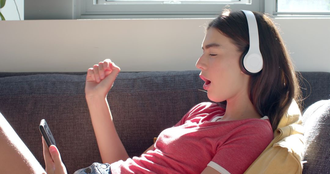 Teenage Girl Enjoying Music on Headphones in Sunny Living Room