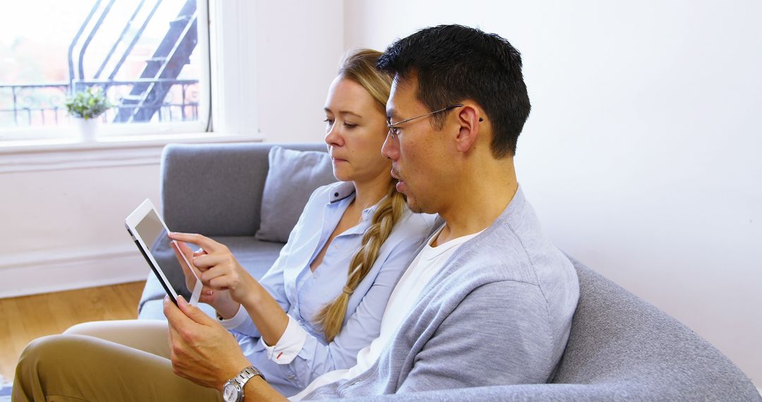 Couple Using Digital Tablet on Sofa at Home