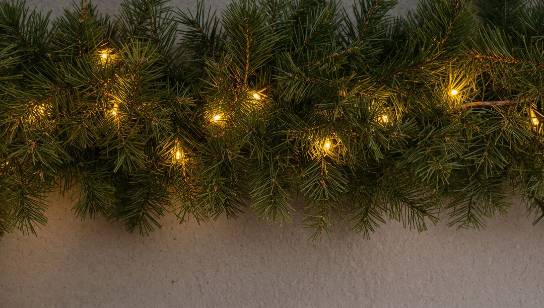 Glowing Pine Garland with Warm White LED Lights on Textured Plaster Wall for Holiday Decor