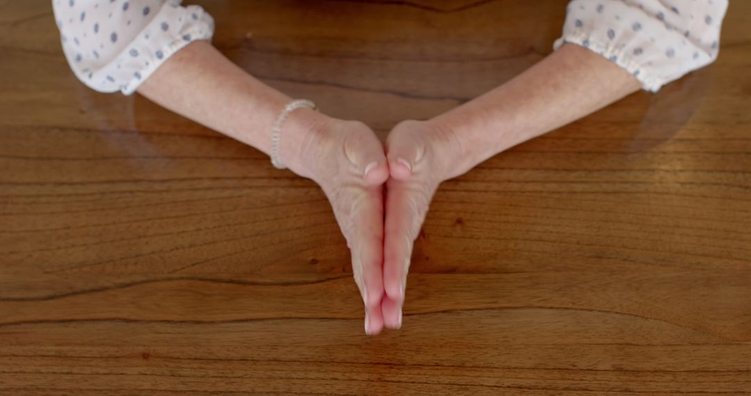 Expressive Hand Gesture on Wooden Table with Bracelet