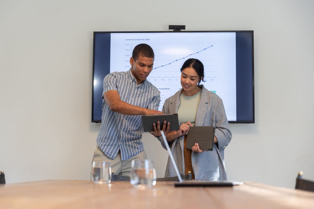 Diverse Coworkers Reviewing Data on Tablets in Modern Office Meeting