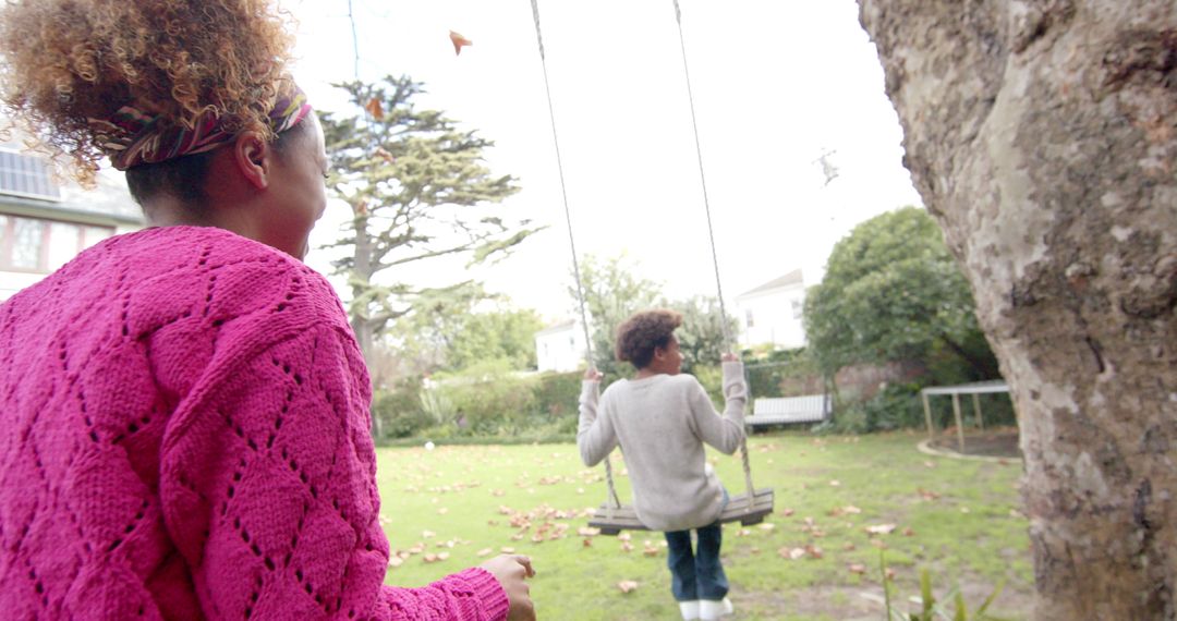 Mother Pushing Son on Swing in Serene Garden