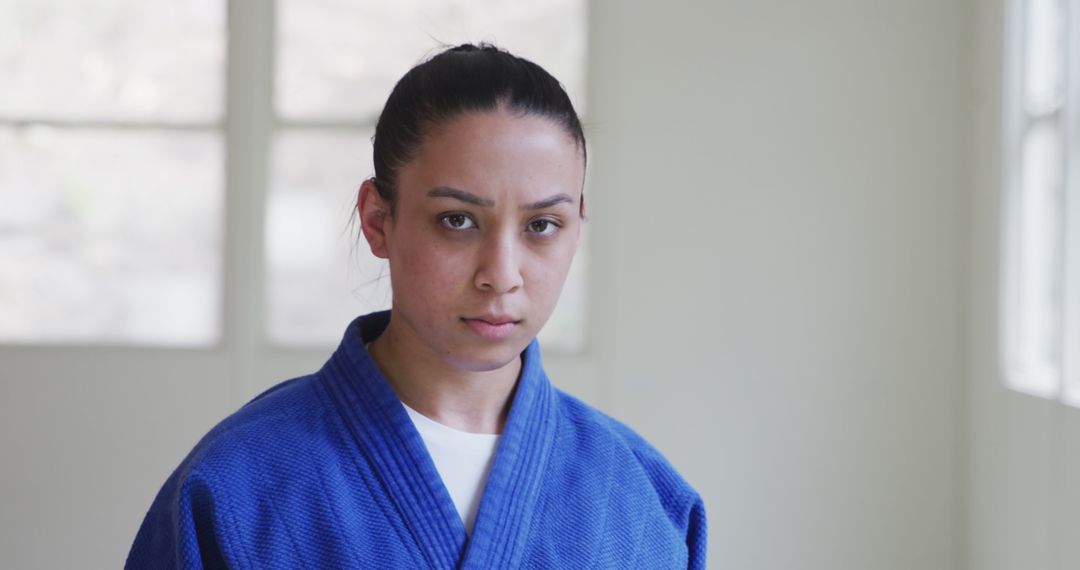 Serious Martial Artist in Blue Gi Looking at Camera in Bright Room - Free Images, Stock Photos and Pictures on Pikwizard.com