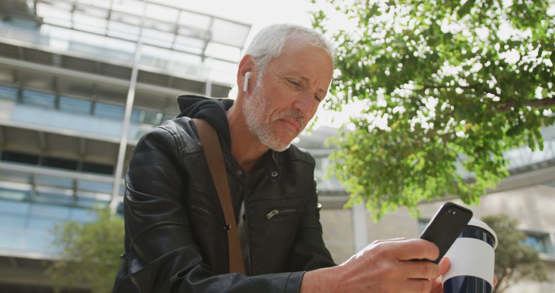 Senior Man Wearing Earbuds Using Smartphone Outdoors - Free Images, Stock Photos and Pictures on Pikwizard.com