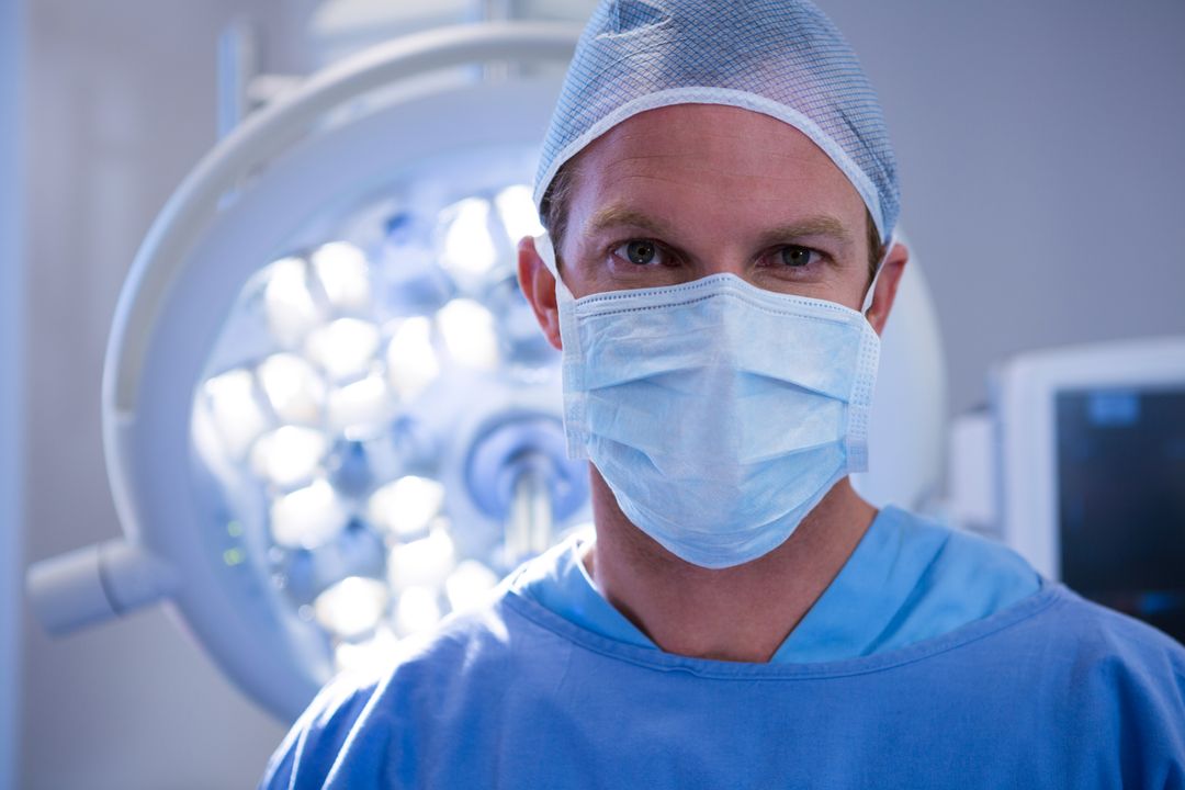 Portrait of male surgeon wearing surgical mask in operation theater - Free Images, Stock Photos and Pictures on Pikwizard.com