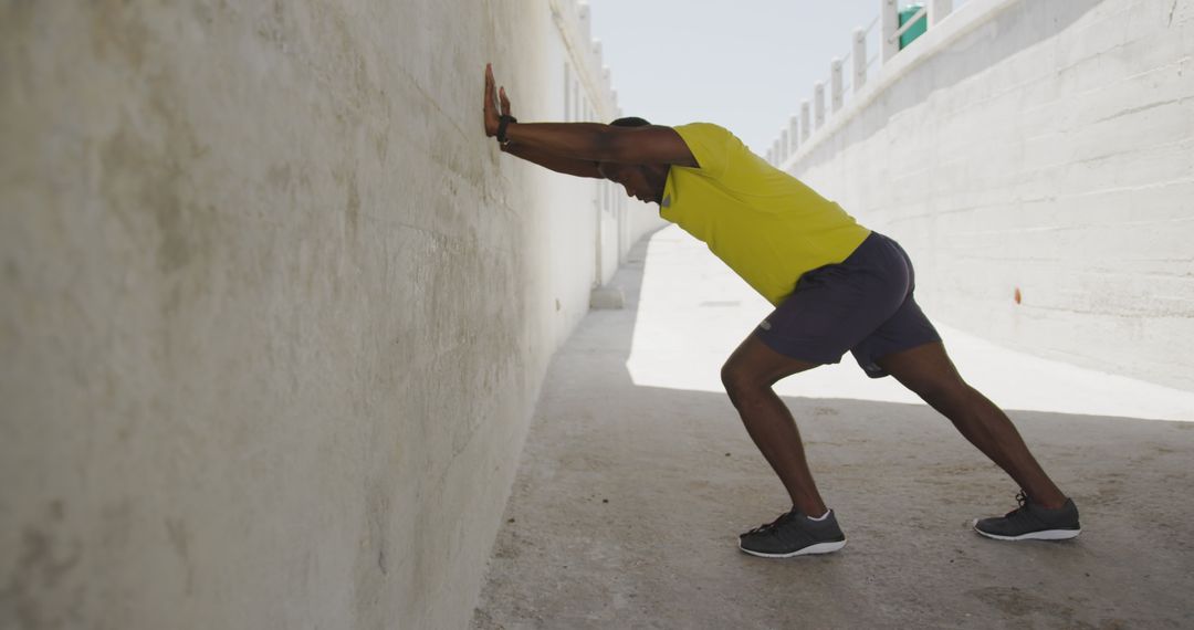 Athletic Man Stretching Against Wall in Urban Outdoor Setting - Free Images, Stock Photos and Pictures on Pikwizard.com