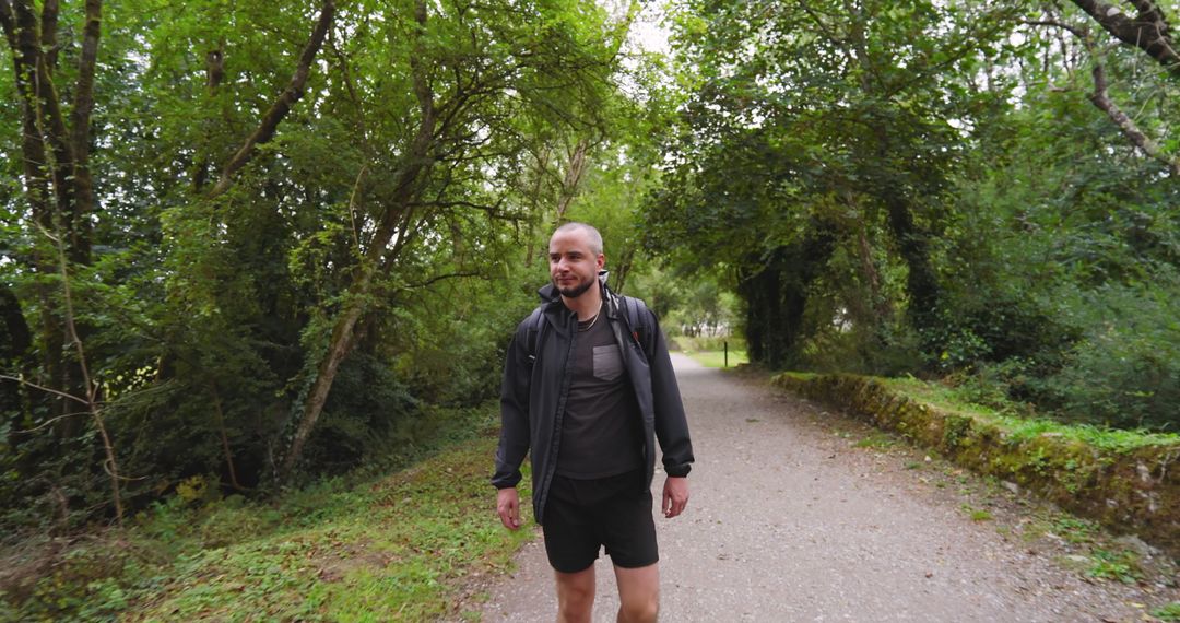 Man Enjoying Serene Stroll on Forest Trail with Headphones