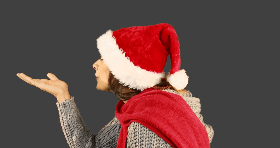 Woman Blowing Kiss Wearing Santa Hat and Red Scarf on Dark Background - Free Images, Stock Photos and Pictures on Pikwizard.com