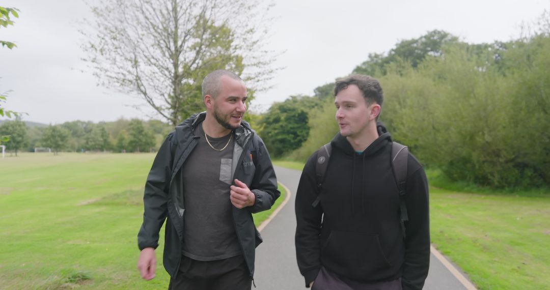 Two Friends Walking in Park Engaging in Relaxing Conversation