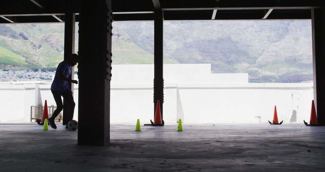 Silhouette of Boy Practicing Soccer Indoors Against Mountain Backdrop - Free Images, Stock Photos and Pictures on Pikwizard.com