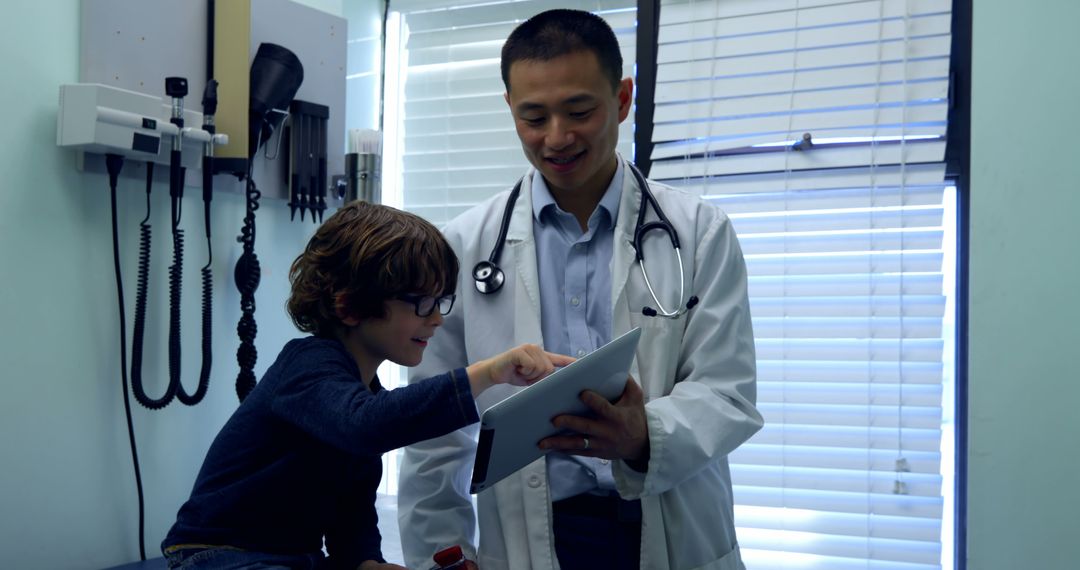 Pediatrician in White Coat Engaging with Young Patient Using Tablet in Clinic - Free Images, Stock Photos and Pictures on Pikwizard.com