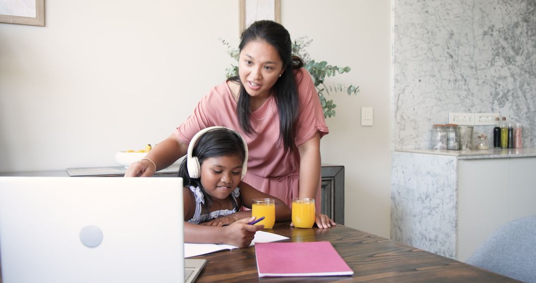 Mother Assisting Daughter with Homework at Kitchen Table