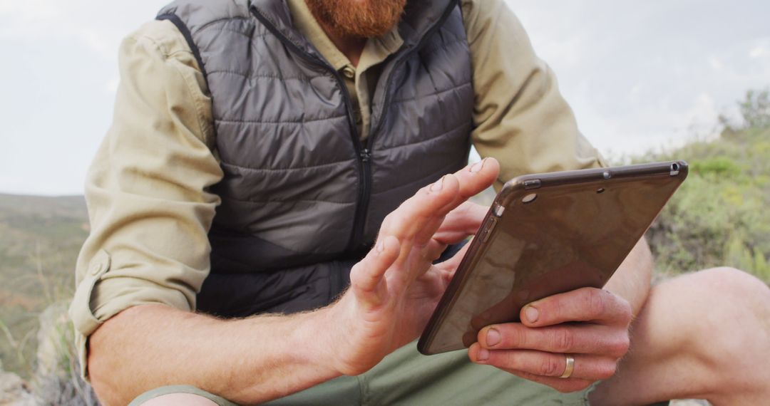 Bearded Man Using Tablet in Outdoor Wilderness Setting - Free Images, Stock Photos and Pictures on Pikwizard.com