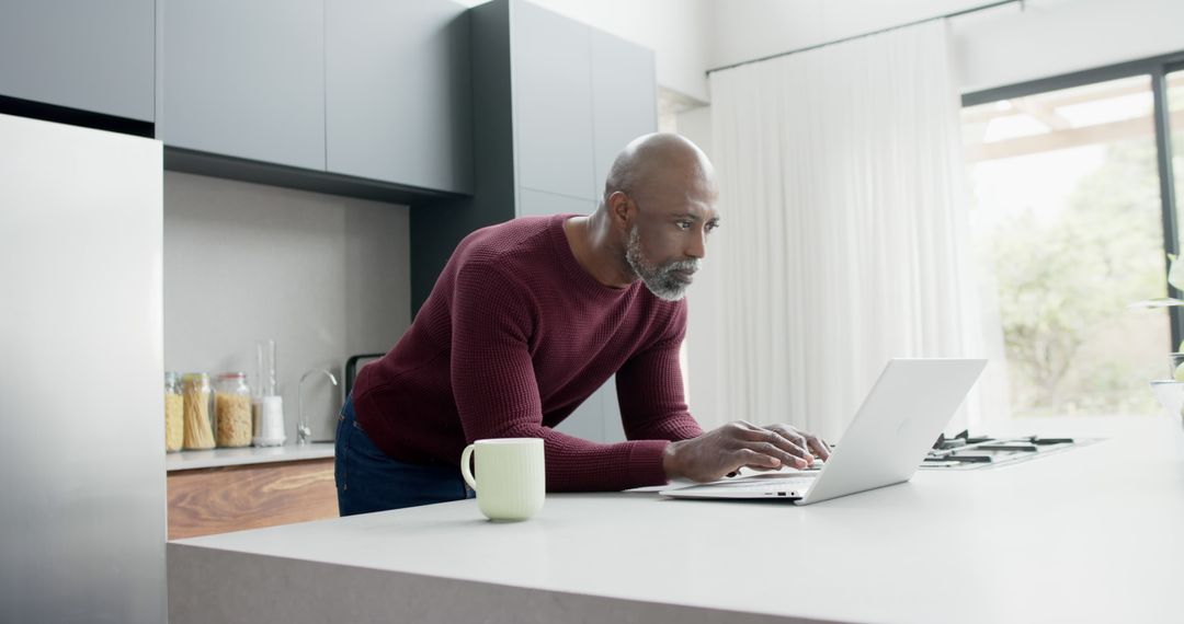 Focused Man Using Laptop in Modern Kitchen - Free Images, Stock Photos and Pictures on Pikwizard.com