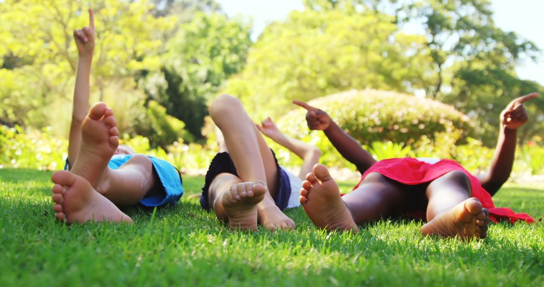 Diverse group of children relaxing on grass together pointing up - Free Images, Stock Photos and Pictures on Pikwizard.com