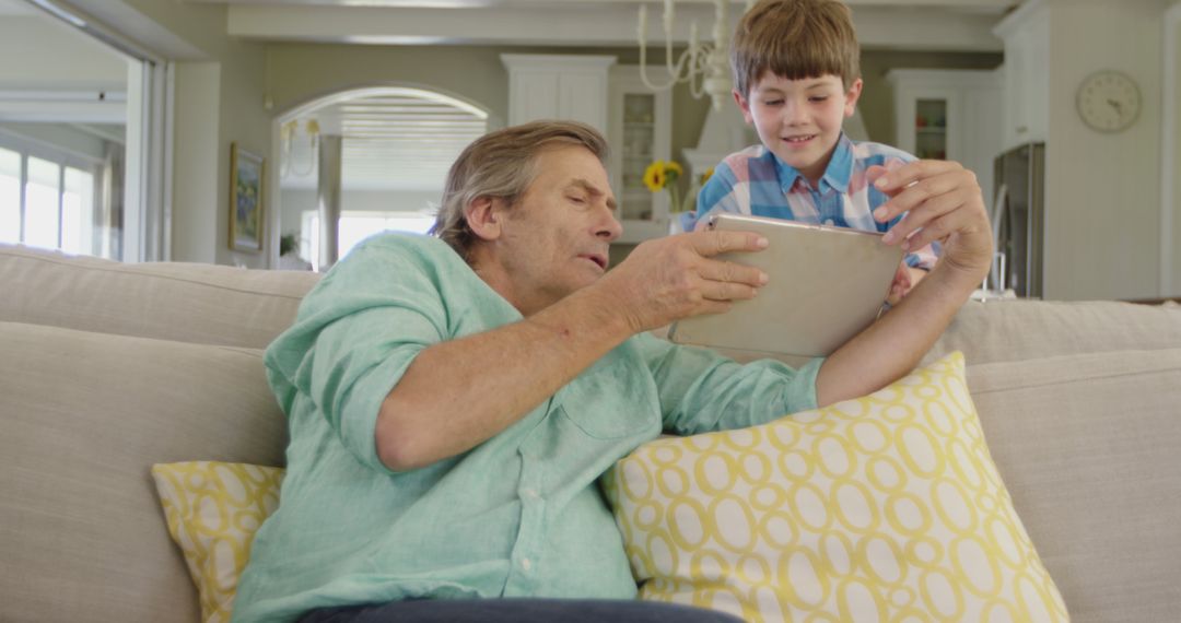 Grandfather and Grandson Using Digital Tablet on Couch - Free Images, Stock Photos and Pictures on Pikwizard.com