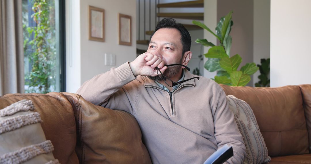 Contemplative Mature Asian Man Relaxing at Home with Notebook