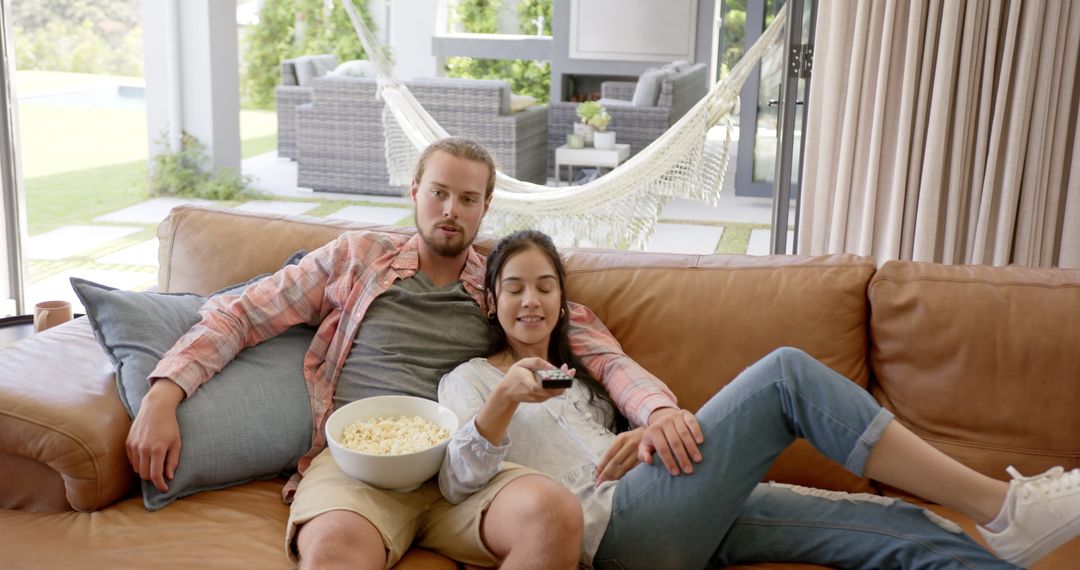Young Couple Relaxing on Sofa Watching Television with Popcorn