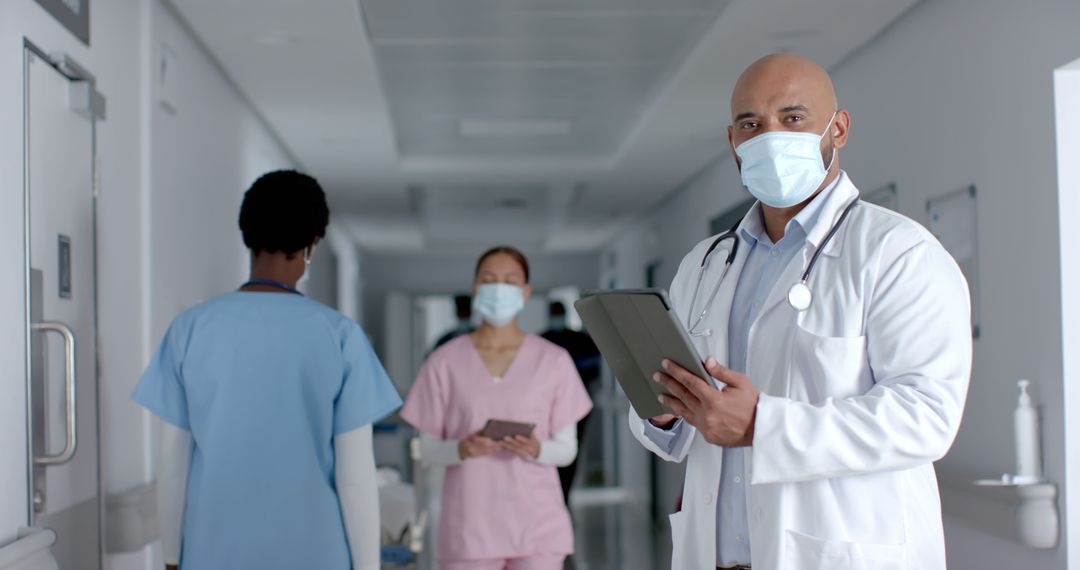 Healthcare Workers in Medical Facility Hallway Wearing Protective Masks - Free Images, Stock Photos and Pictures on Pikwizard.com