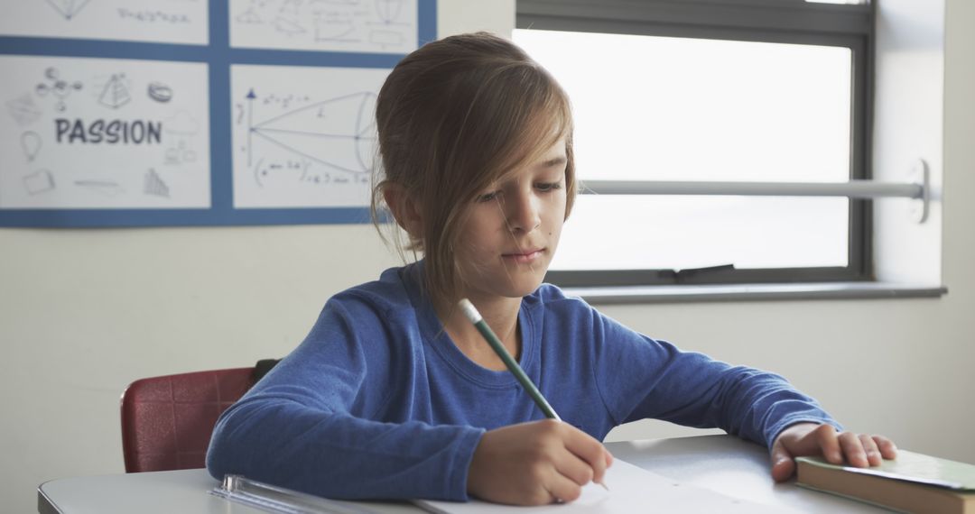 Boy Concentrating While Writing in Classroom