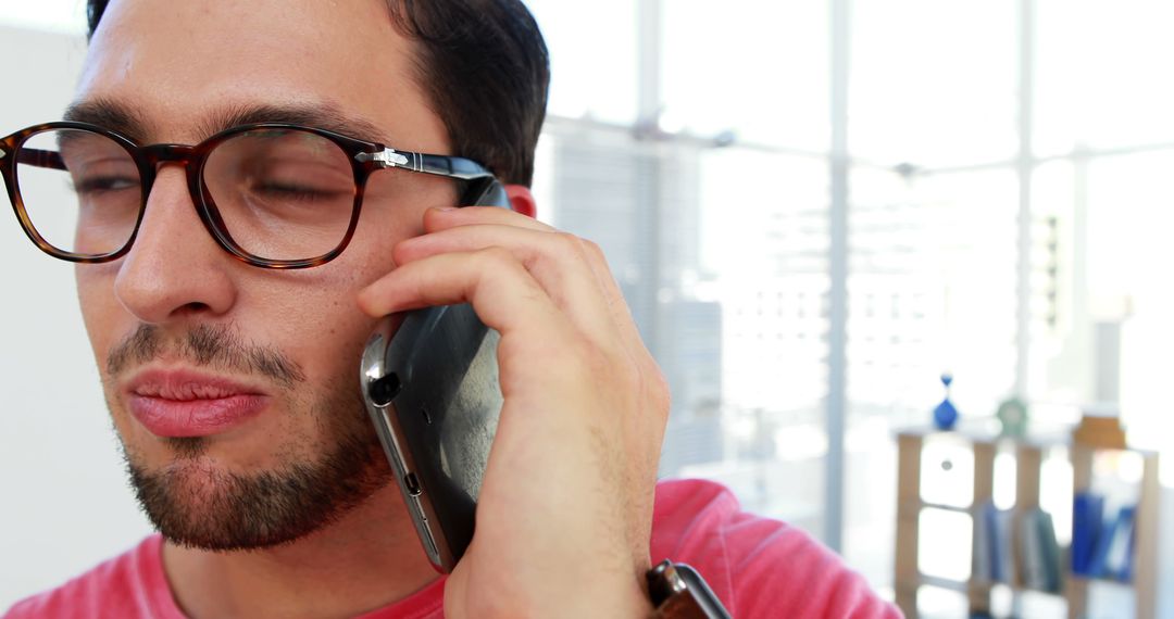 Man with glasses talking on smartphone in modern office - Free Images, Stock Photos and Pictures on Pikwizard.com