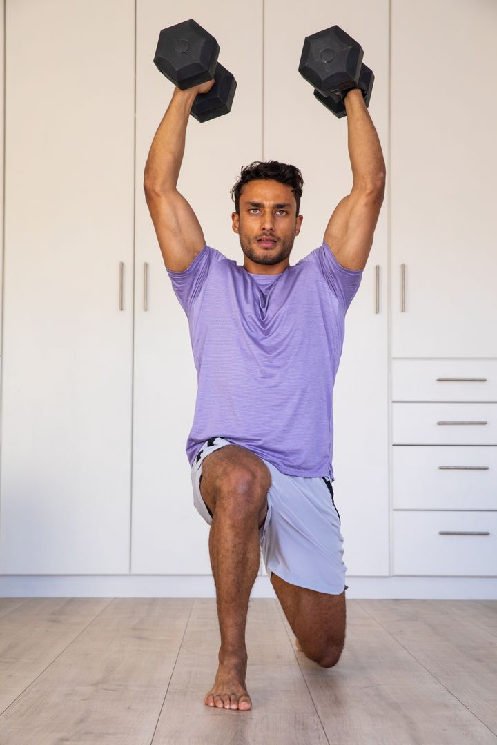 Man Practicing Overhead Dumbbell Lunge in Home Gym