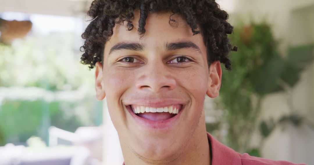 Happy Young Man with Curly Hair Smiling Outdoors - Free Images, Stock Photos and Pictures on Pikwizard.com