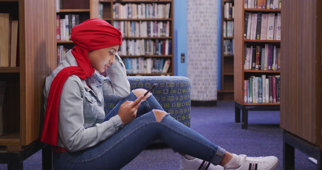 Young Woman in Red Hijab Using Smartphone in Library - Free Images, Stock Photos and Pictures on Pikwizard.com